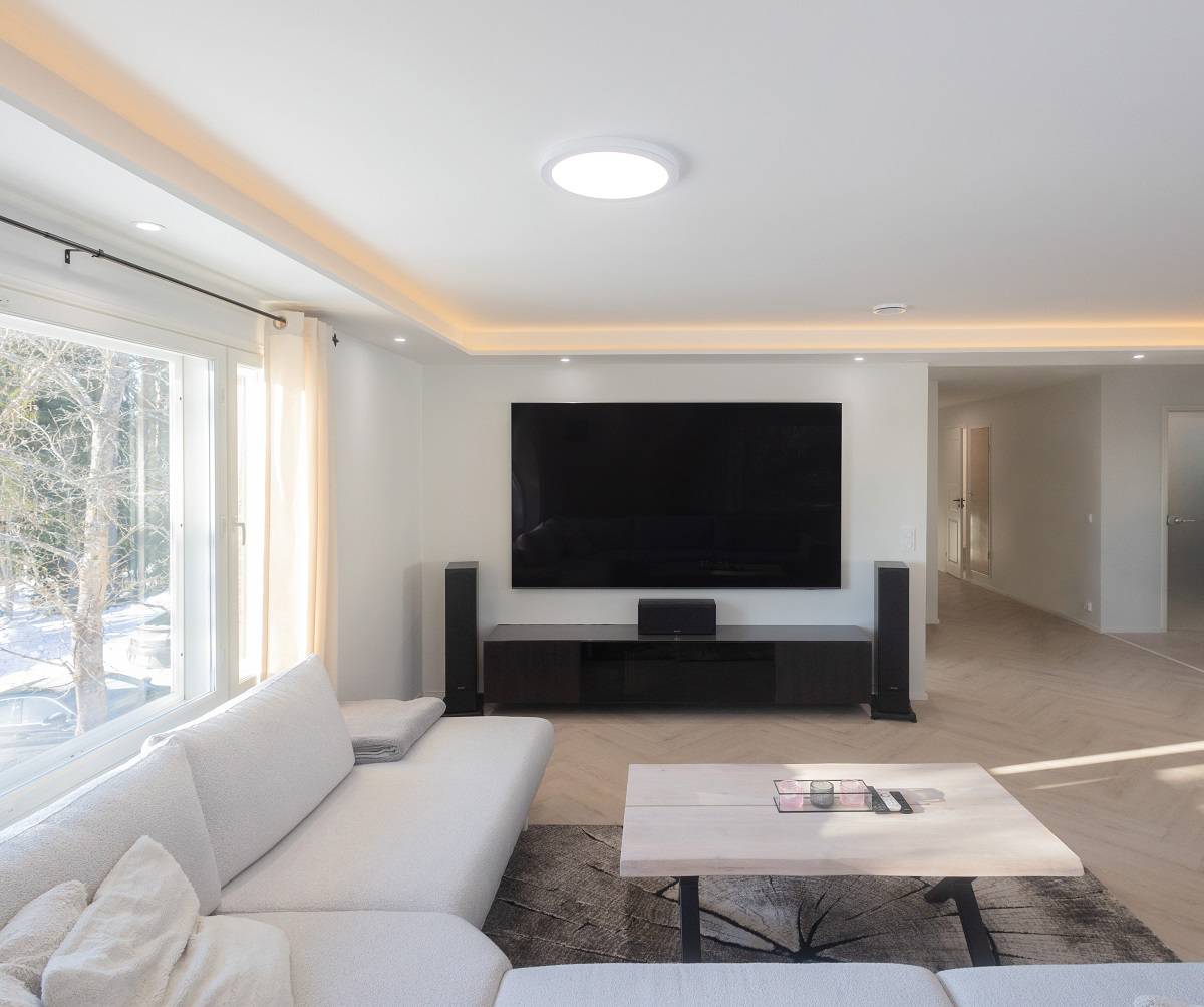 Living room with partially lowered ceiling with LED strip, LED spotlights and a ceiling light in the middle.